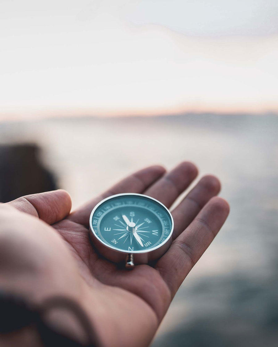 a hand holding a compass with a blurry background